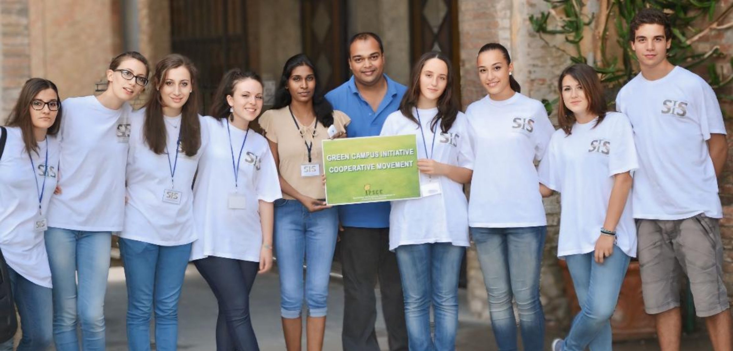 Dr. Edwin with international participants at the SMPT Summer School in Todi, Italy, holding the Green Campus Initiative Cooperative Movement banner